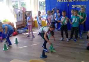 Dzieci podczas konkurencji- slalom z piłeczką toczoną przy użyciu klapki na muchy.